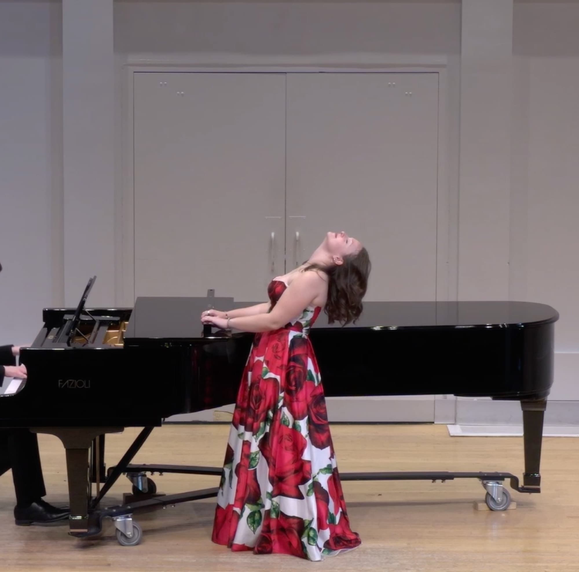 Brynn Jacobs performing in a floral gown beside a grand piano